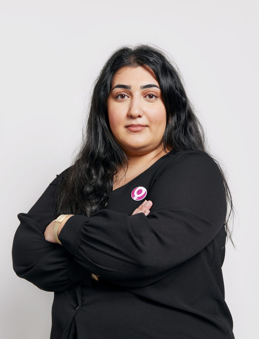 Roks ordförande Adine Samadi lätt leende med armarna i kors mot vit bakgrund.